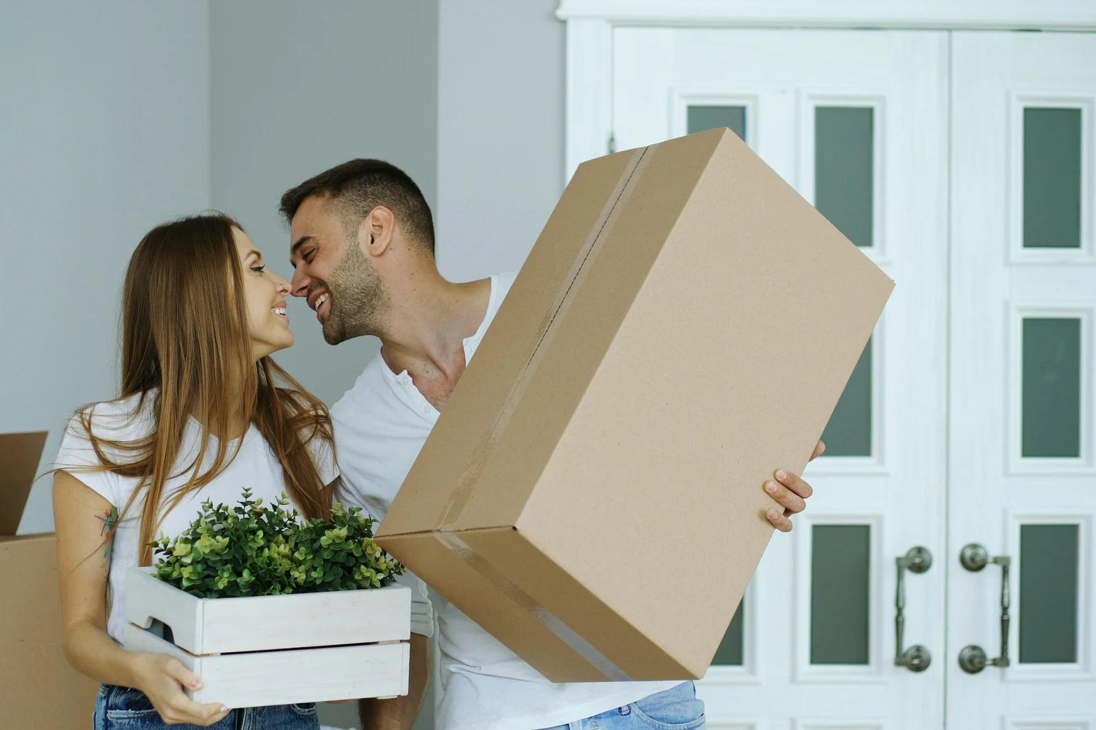 A couple carrying moving boxes into their new home